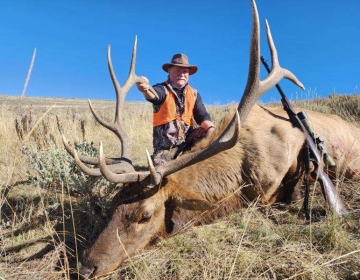 Hunter posing with his bull elk and rifle